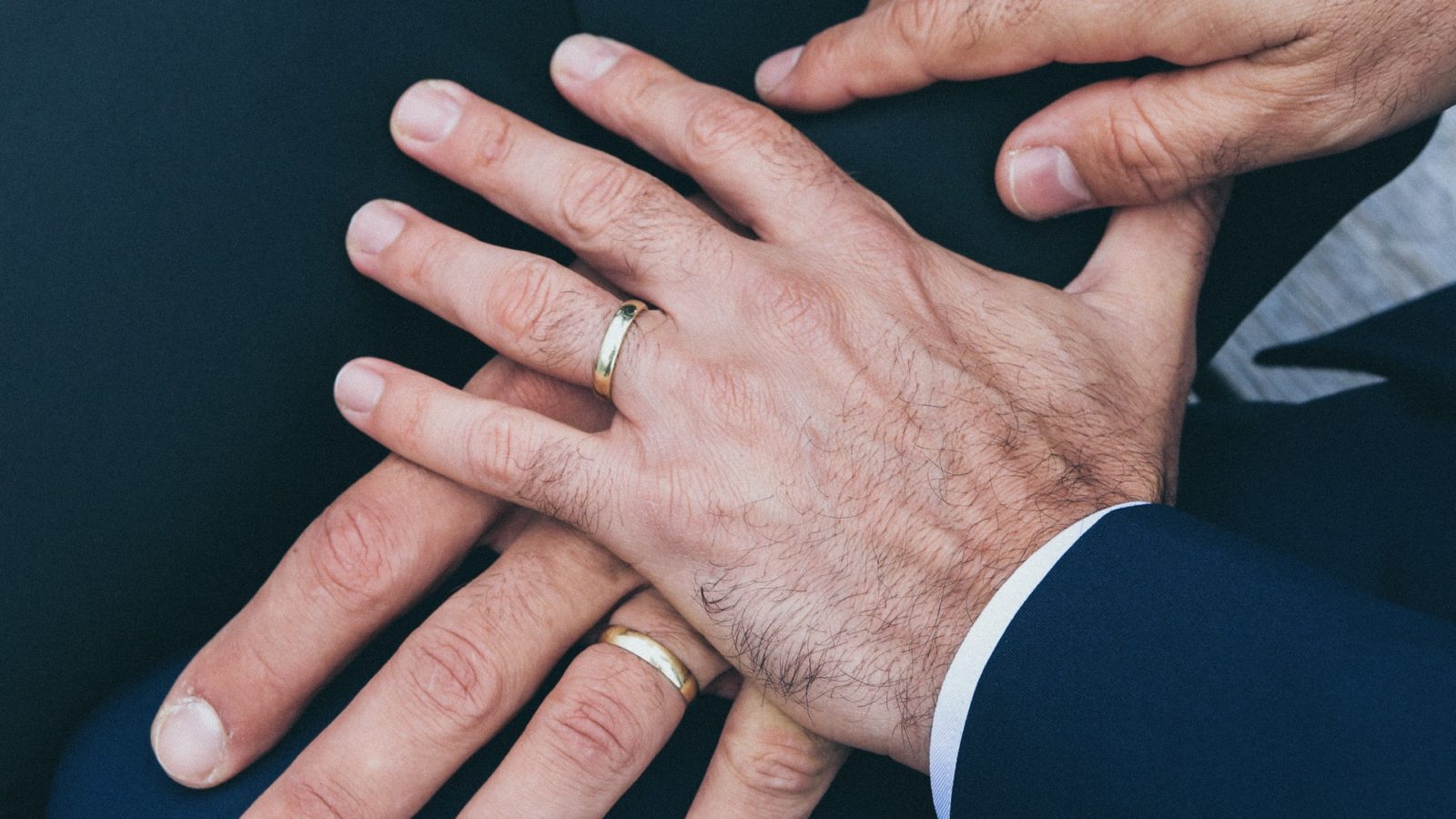Two men's hands with wedding rings representing the laws governing same-sex divorce in Canada