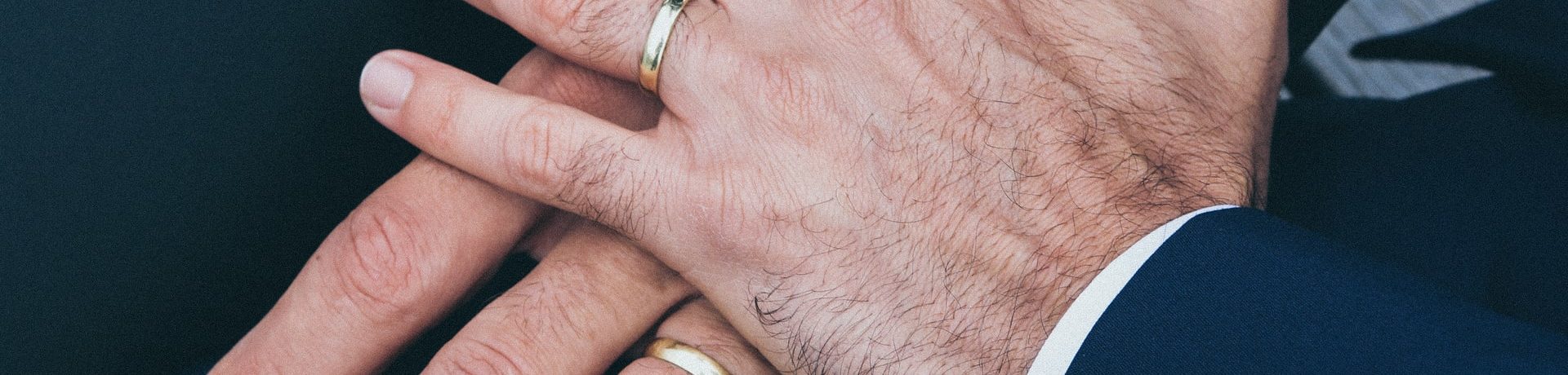 Two men's hands with wedding rings representing the laws governing same-sex divorce in Canada