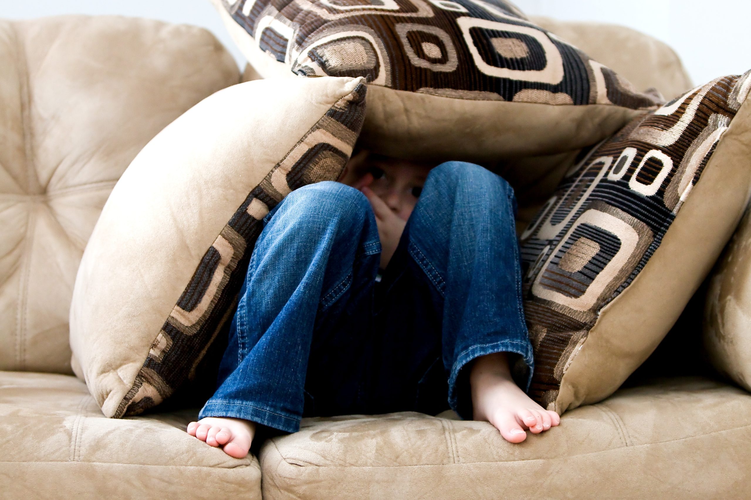 Child hiding under pillows representing parental alienation during a high-conflict divorce or separation